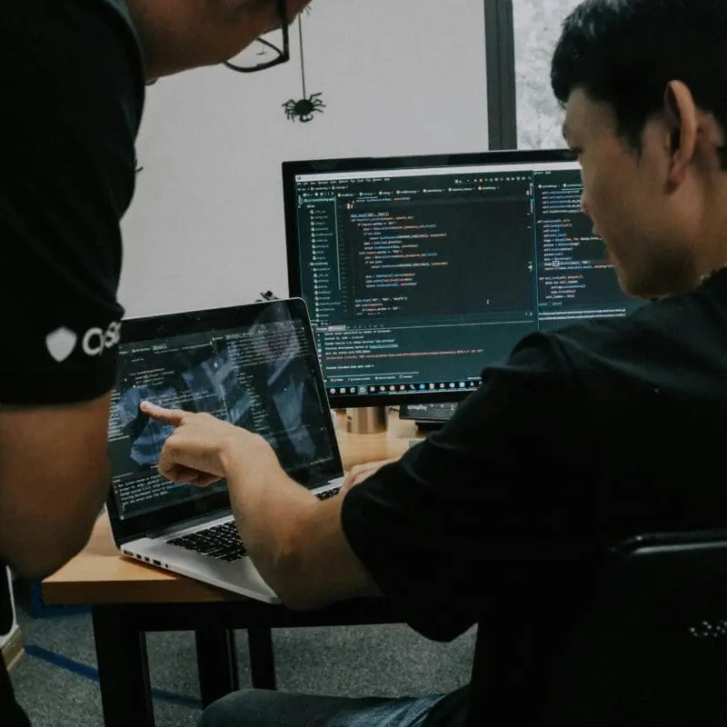 An image of a man sat at a computer, with a technical interface on the screen.
