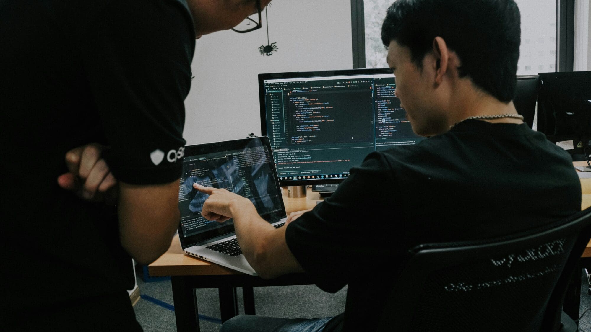 An image of a man sat at a computer, with a technical interface on the screen.